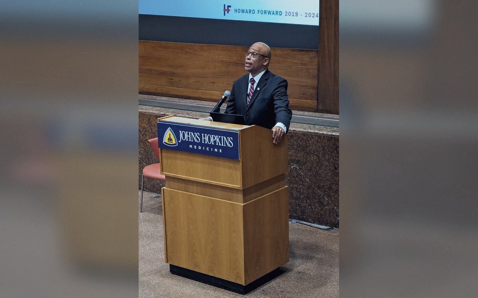 A man in a suit speaks at a Johns Hopkins Medicine podium during an event