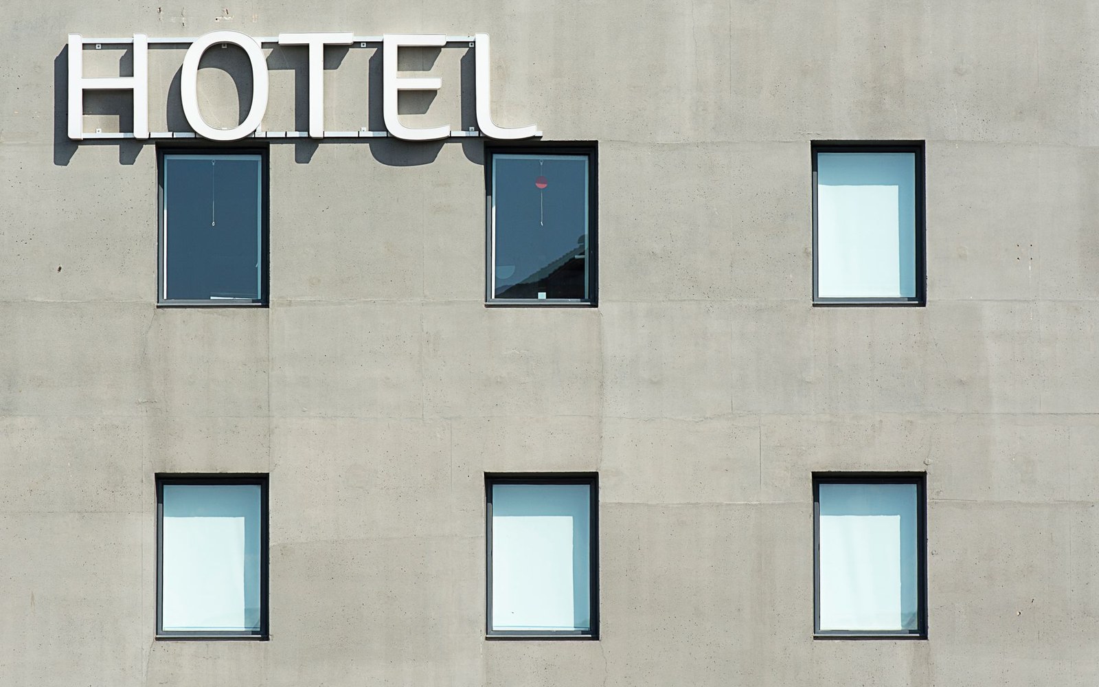 Concrete hotel facade with rows of dark-framed windows below a large "Hotel" sign