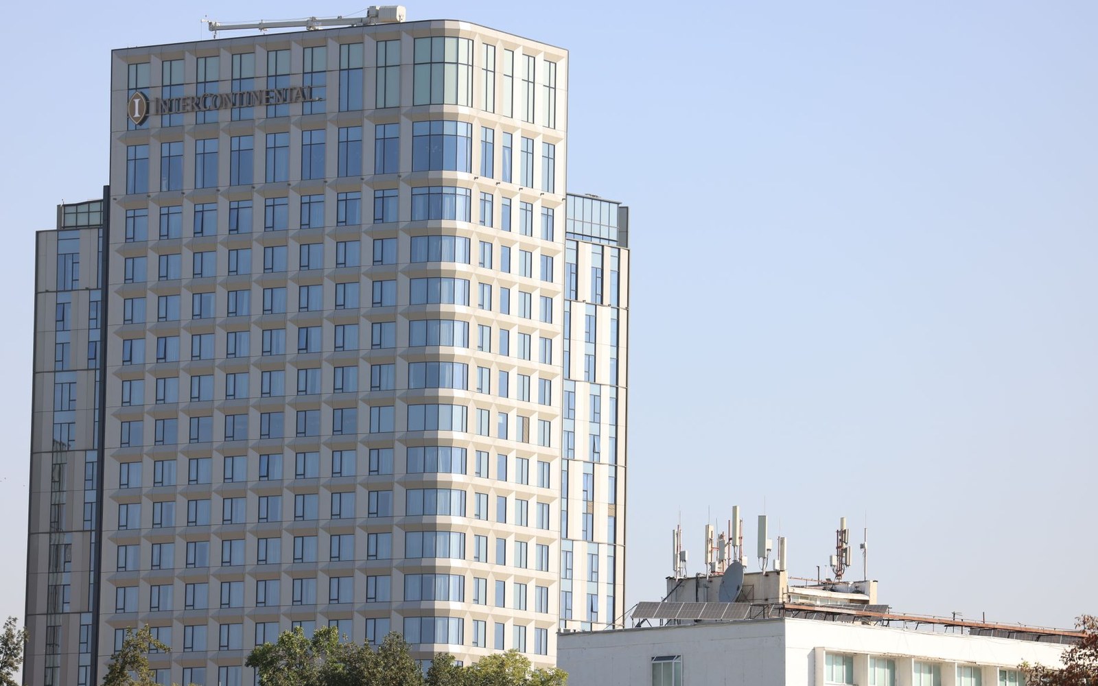 InterContinental hotel tower rises above a lower rooftop with communication antennas